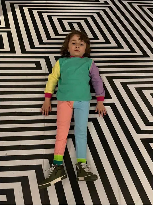 Child standing on a black and white geometric patterned floor