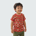 Child wearing a red t-shirt with a pattern of green leaves and pink radish on a white background
