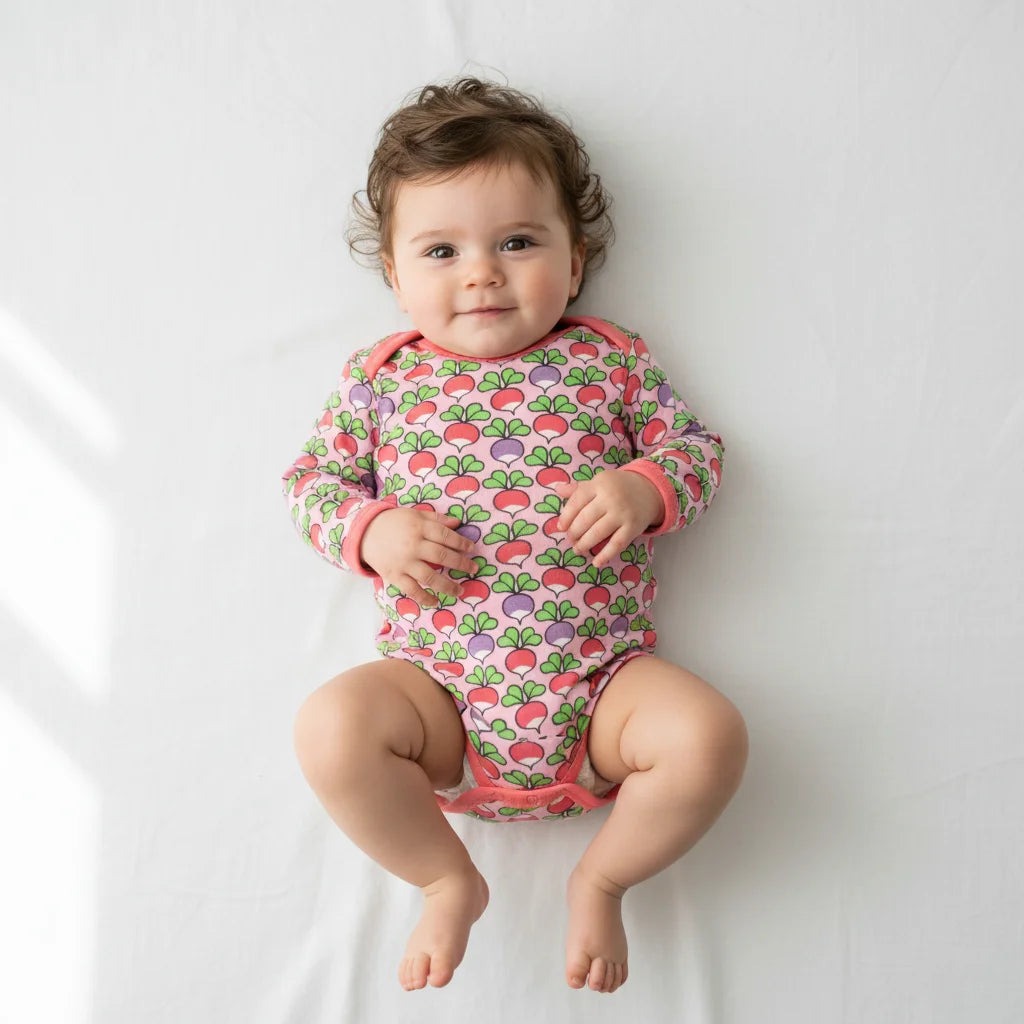 Baby wearing a colorful onesie with a strawberry pattern on a white background