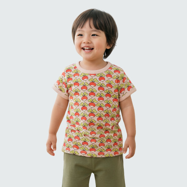 Child wearing a shirt with a radish pattern on a white background