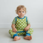 Baby wearing a green and blue outfit with clover pattern on a white background