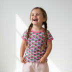 Young girl wearing a colorful patterned shirt with braided hair on a white background