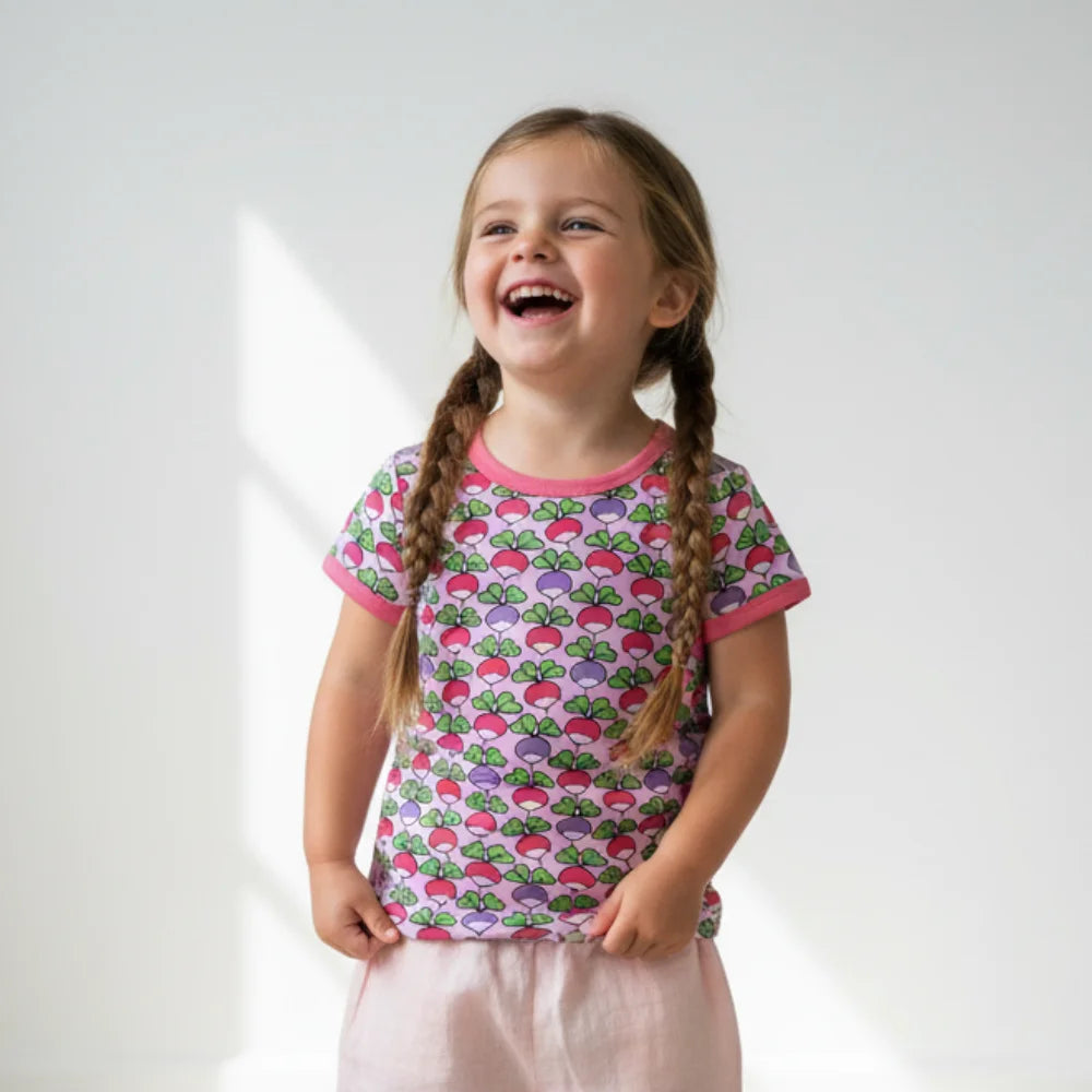 Young girl wearing a colorful patterned shirt with braided hair on a white background