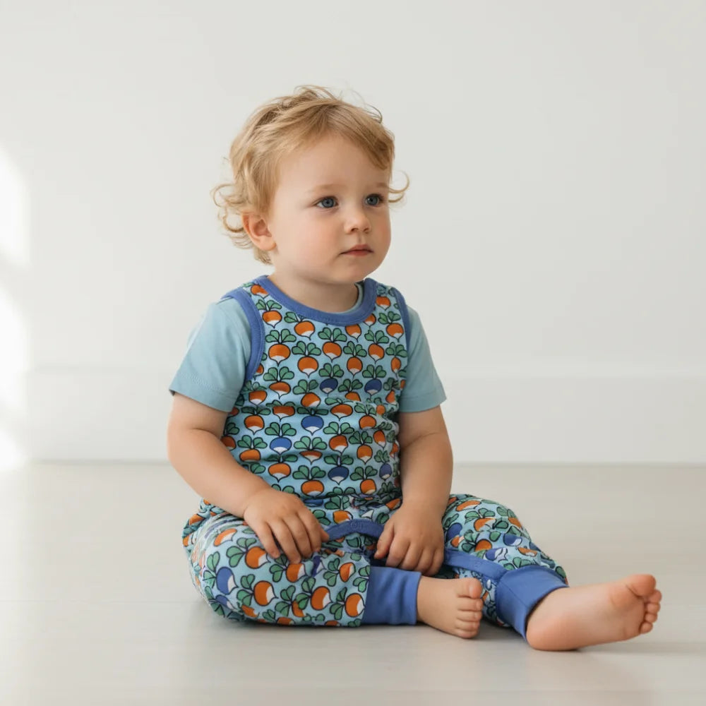 infant wearing a colorful outfit with a pattern of radish on a plain background