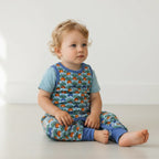 infant wearing a colorful outfit with a pattern of radish on a plain background