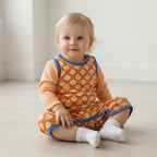 baby wearing an orange and blue outfit play sui9t with a white background