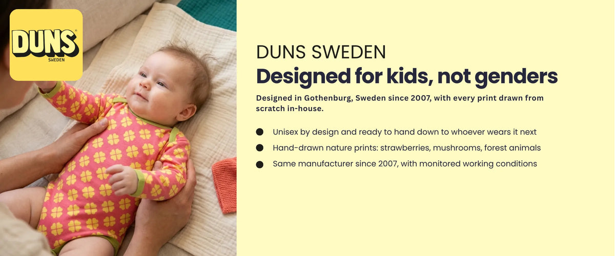 Baby in a DUNS Sweden pink and yellow clover print organic bodysuit. DUNS Sweden, designed for kids, not genders. 