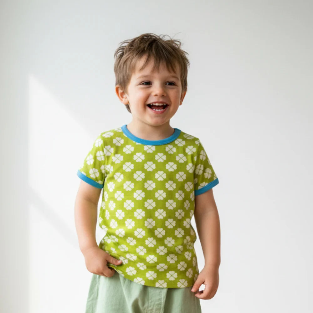 Child wearing a green shirt with white patterns against a plain background