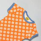 Orange romper with white clover pattern and blue trim on a gray background