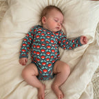 infant wearing a radish duns sweden bodysuit onesie lying on a bed