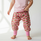 Child wearing a pink shirt and strawberry-patterned pants on a white background