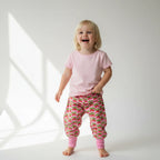 Child wearing a pink shirt and strawberry-patterned pants on a white background