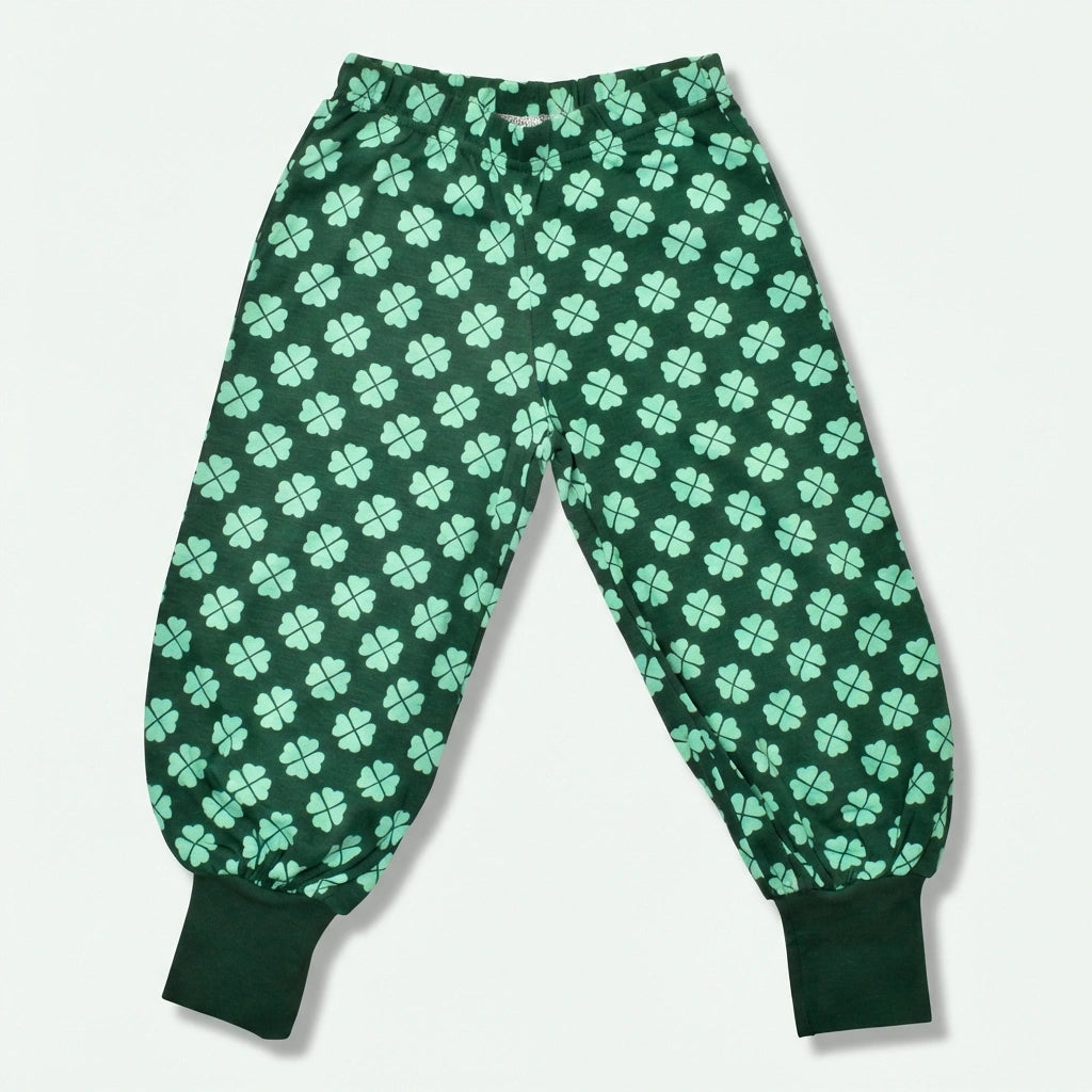 Green pajama pants with a four-leaf clover pattern on a light gray background