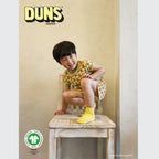 Child sitting on a wooden chair wearing a colorful outfit with Duns Sweden branding.