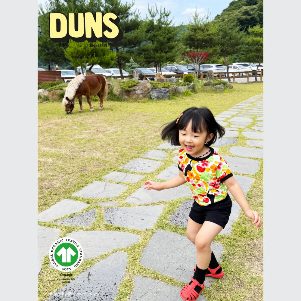 Child walking on a stone path with a pony in the background, featuring the DUNS brand.