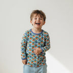Child wearing a colorful patterned shirt with a plain background