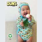 Baby wearing a colorful outfit with DUNS Sweden branding and organic certification logo.
