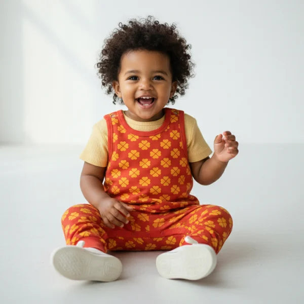 Child wearing a red and yellow checkered outfit with a white background