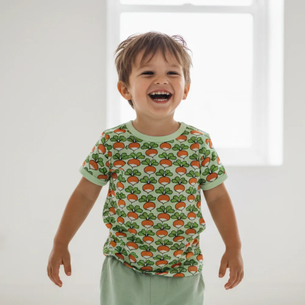 Child wearing a shirt with a carrot pattern in a bright room