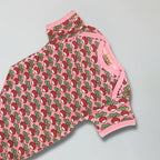 Pink romper with red and green pattern on a gray background