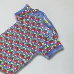 Children's romper with apple pattern on a gray background