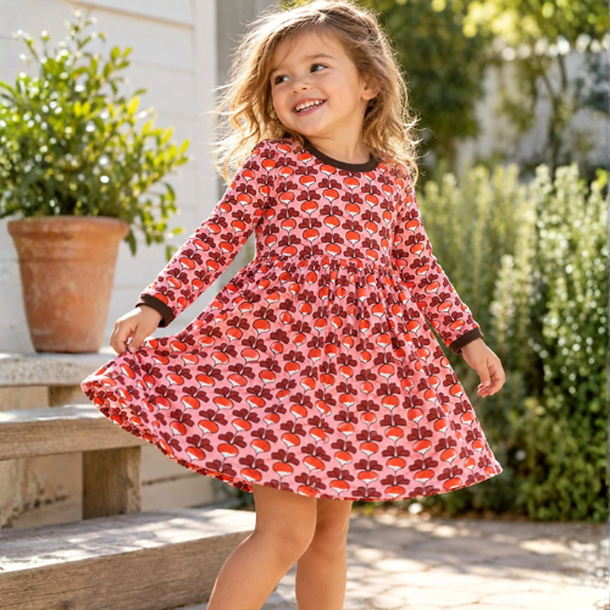 Girl twirling in the DUNS Sweden Radish Pink Gather Dress in organic cotton, long sleeves and a full skirt