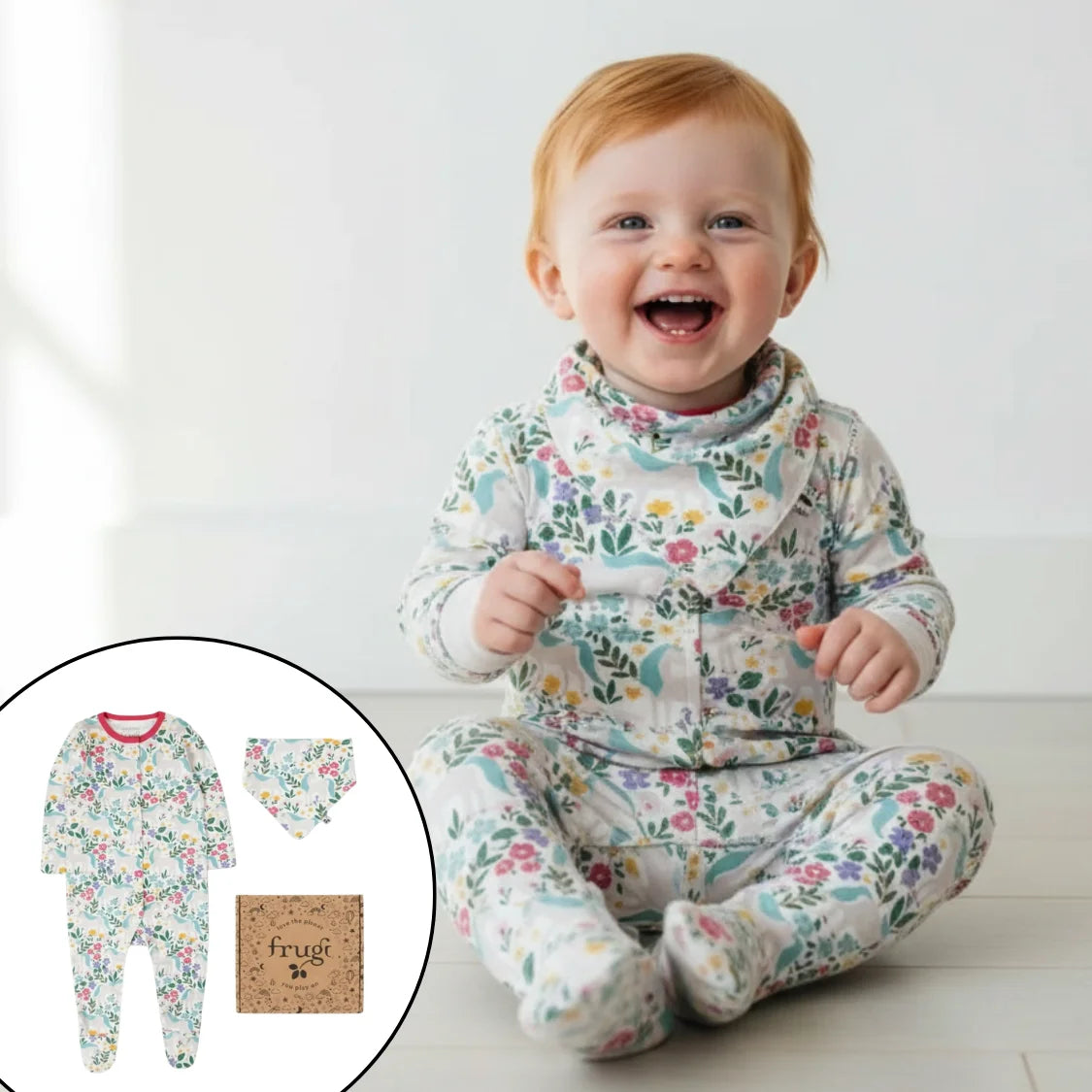 Baby wearing a floral outfit with a bib, sitting on a white floor.