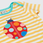 Yellow and white striped baby dress with a colorful ladybug patch on a white background