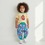 Child wearing a striped shirt with a ladybug design and colorful pants on a white background