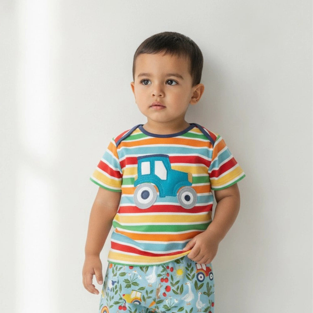 Child wearing a colorful striped shirt with a truck design on a plain background