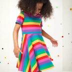 Girl twirling in the Frugi Sunshine Skater Dress, the rainbow striped circular skirt flaring out
