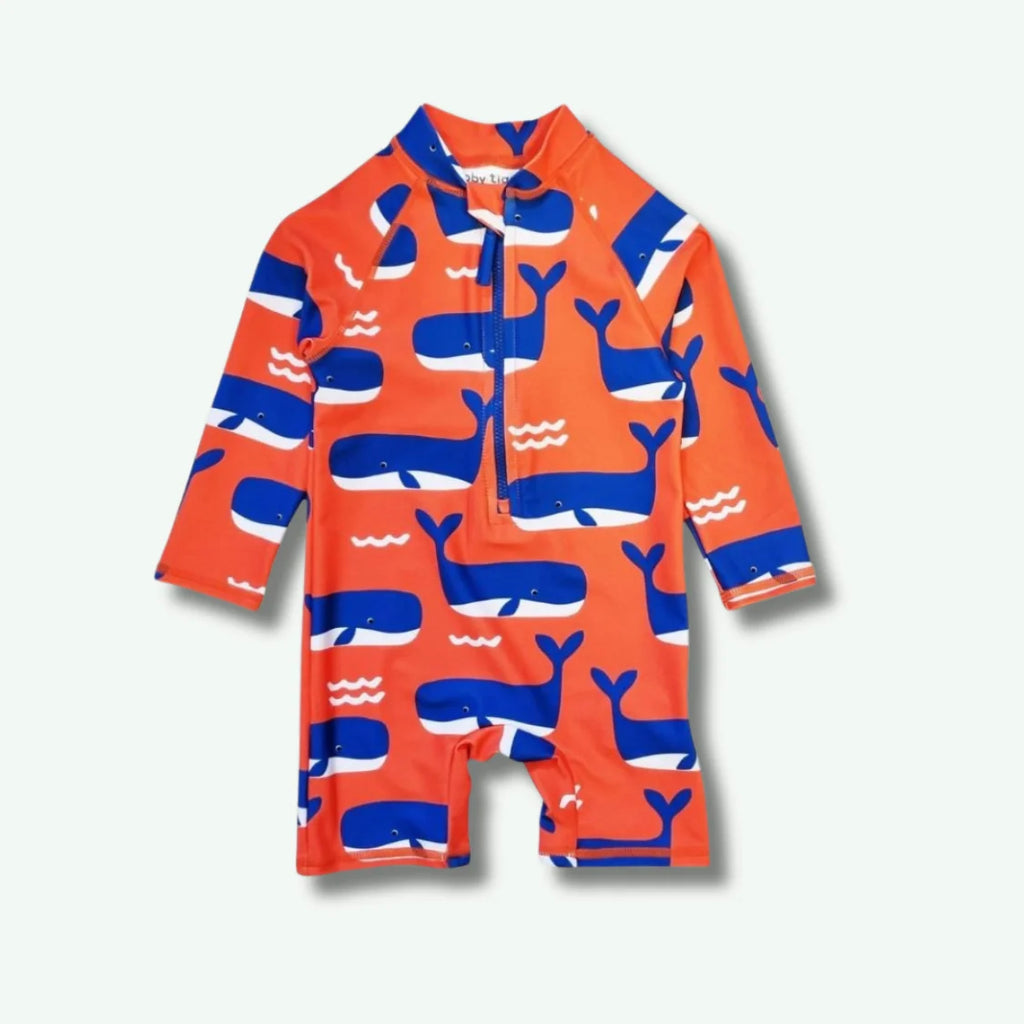 Orange children's swimsuit with blue whale pattern on a white background