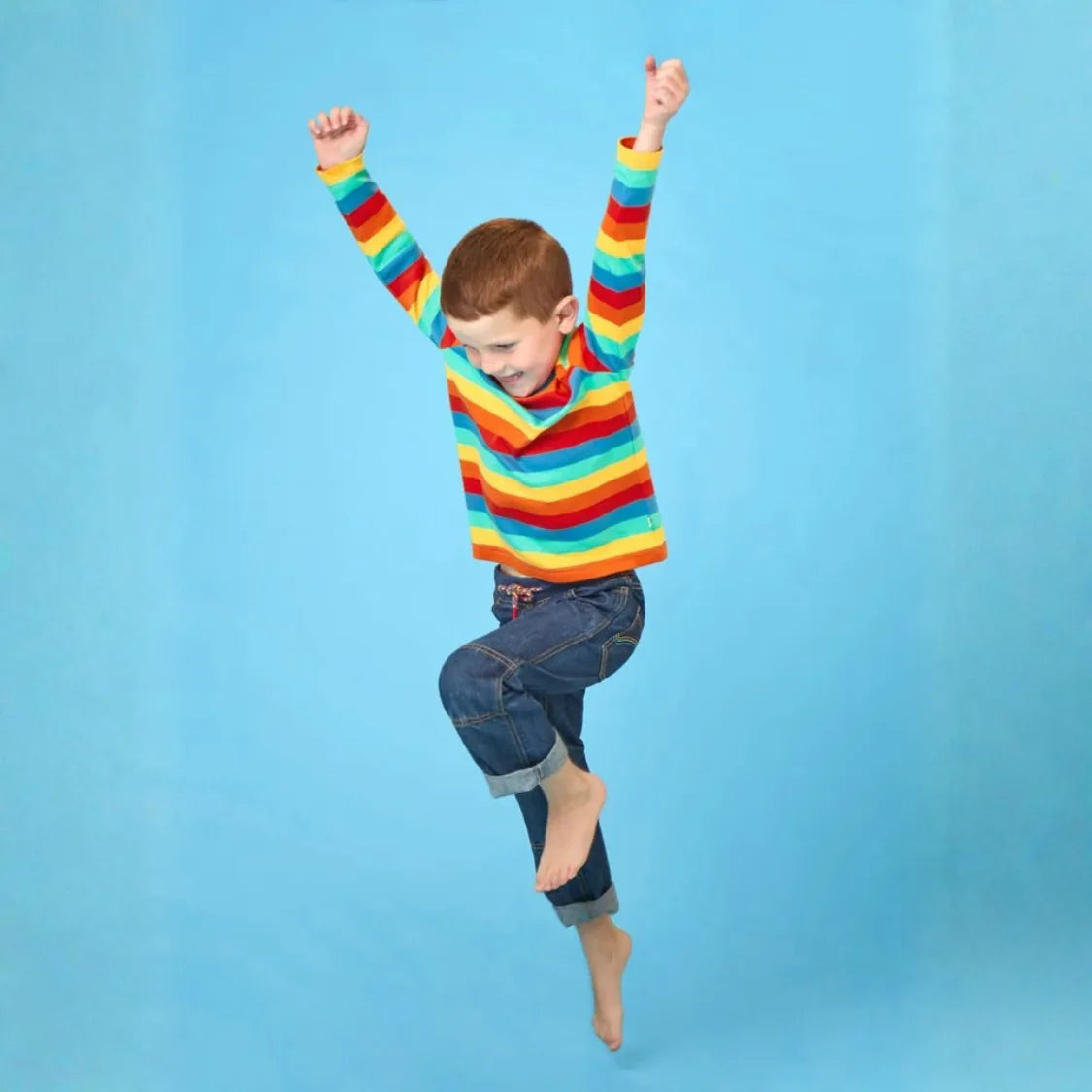 Boy wearing bright organic frugi top jumping