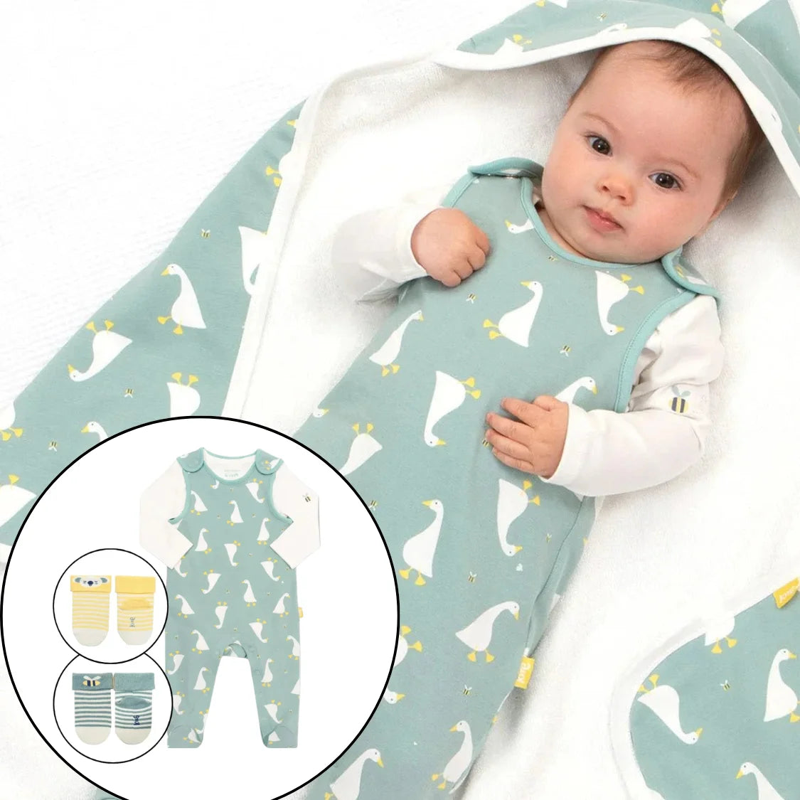 Baby wearing a green baby grow with duck pattern, surrounded by matching items.