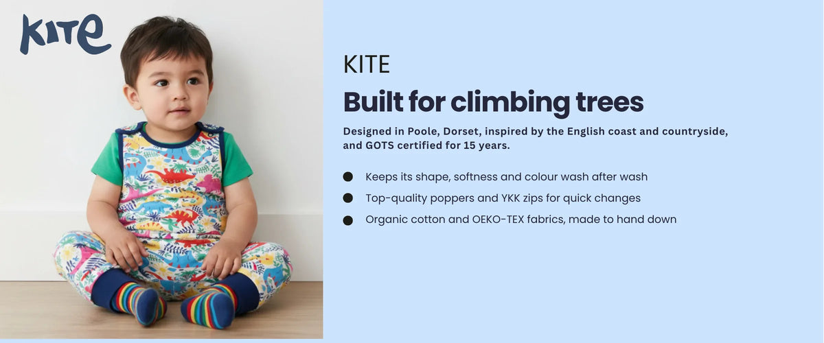 Toddler in a Kite dinosaur print outfit and rainbow socks. Kite, built for climbing trees. Designed in Poole, Dorset, and GOTS certified for 15 years. Holds its colour wash after wash, quality poppers and YKK zips, made to hand down.