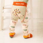A child's lower body wearing patterned leggings with a hedgehog design and autumn leaves, featuring an orange waistband that reads 'Blade & Rose'.