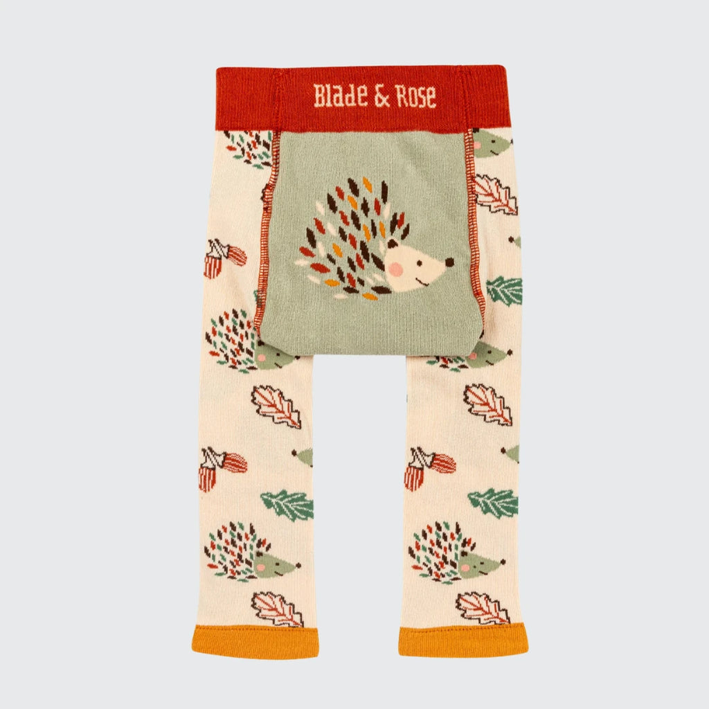 Toddler leggings from Blade & Rose featuring a woodland hedgehog and autumn leaf pattern on a cream base, with a sage green front pocket and a red waistband.