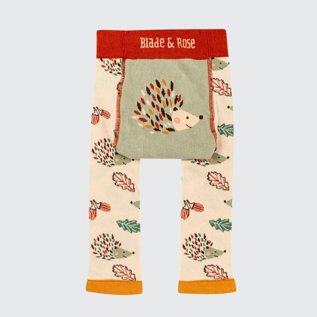 Toddler leggings from Blade & Rose featuring a woodland hedgehog and autumn leaf pattern on a cream base, with a sage green front pocket and a red waistband.