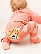 Baby in pink outfit with a jaguar patch on a light background