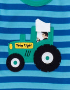 Close-up of a children's shirt with a green tractor design and 'Toby Tiger' branding on a blue and green striped background.