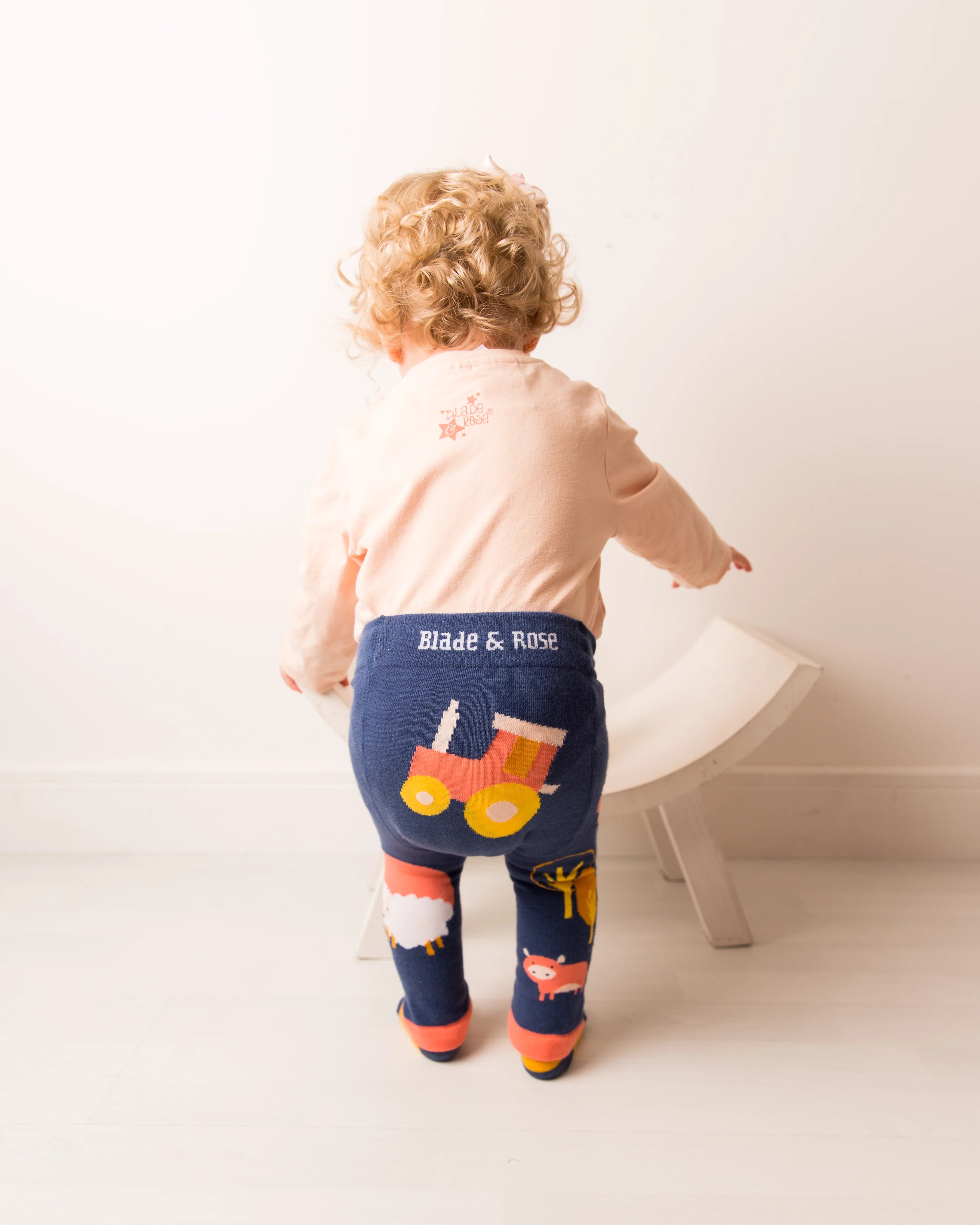 Child wearing navy leggings with a train design and 'Blade & Rose' branding, standing on a white floor.