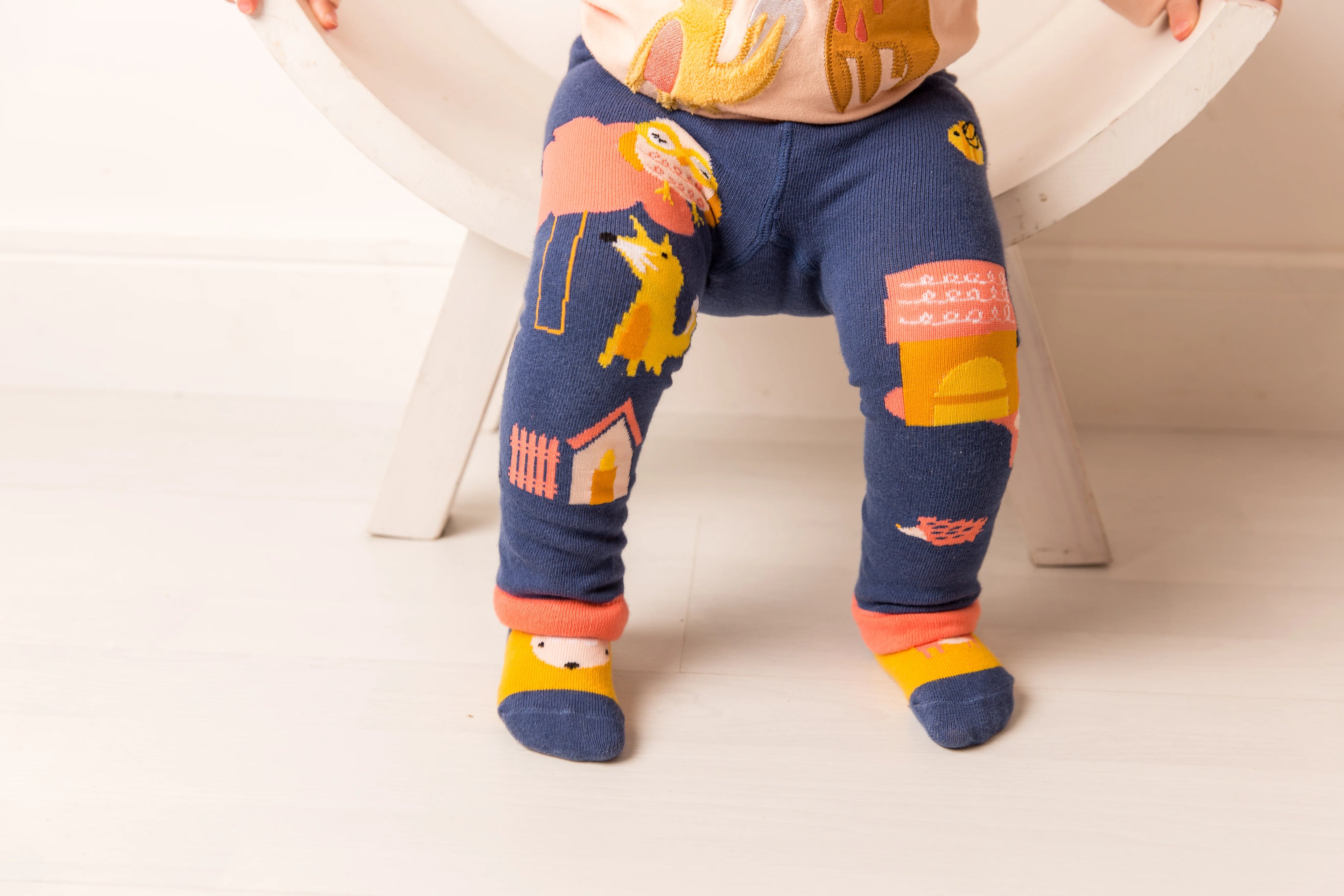 Child wearing colorful leggings with animal prints on a white background