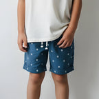 Person wearing blue shorts with white diamond pattern on a plain background
