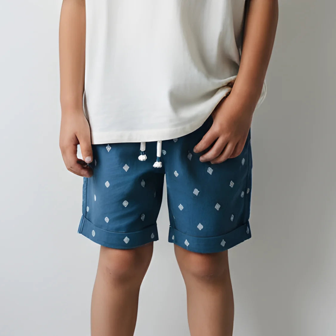 Person wearing blue shorts with white diamond pattern on a plain background