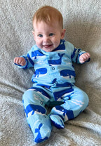 Baby wearing a blue onesie with whale patterns on a textured surface