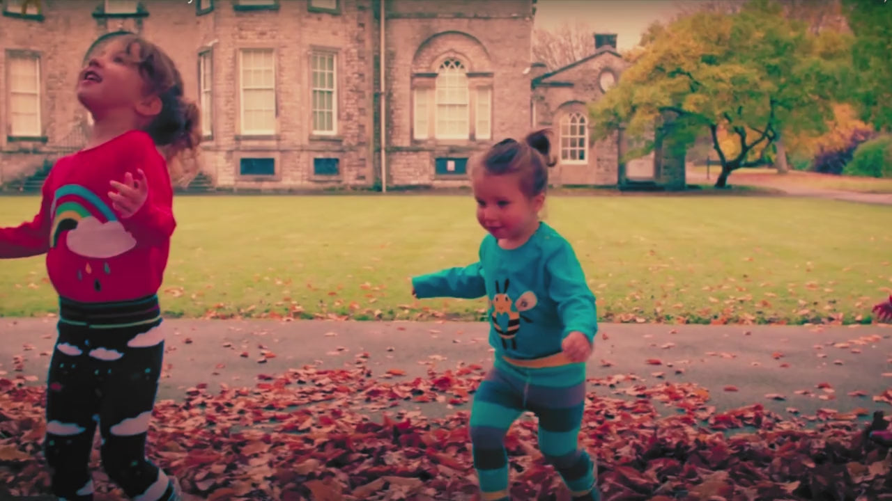 Children playing in leaves in bright organic kids clothes