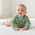 Baby wearing a colorful onesie sitting on a white surface