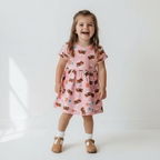 Young girl wearing a pink dress with dog pattern on a white background