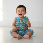 Baby wearing a colorful romper with a turtle pattern on a white background