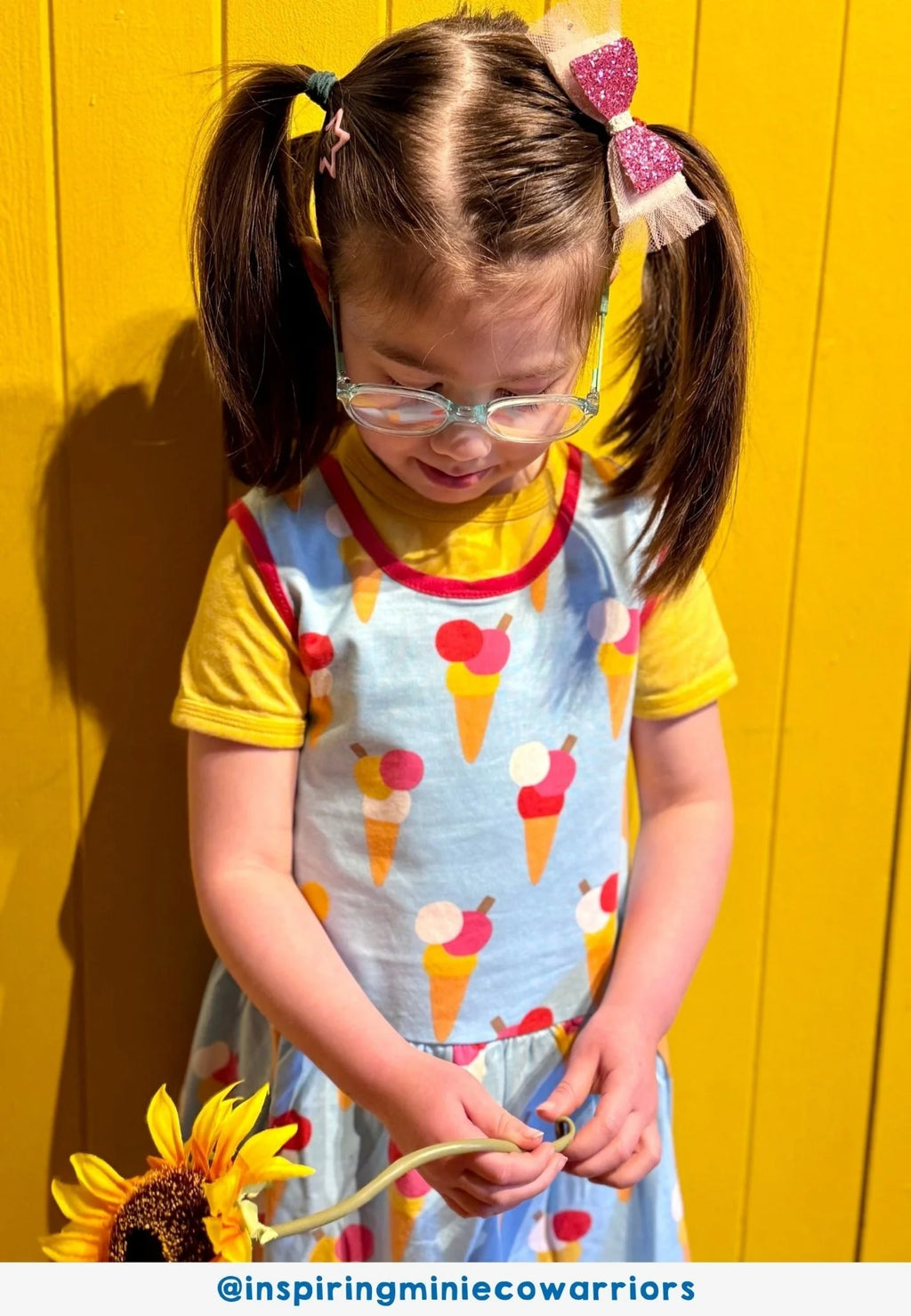Child wearing a colorful dress with ice cream patterns against a yellow background